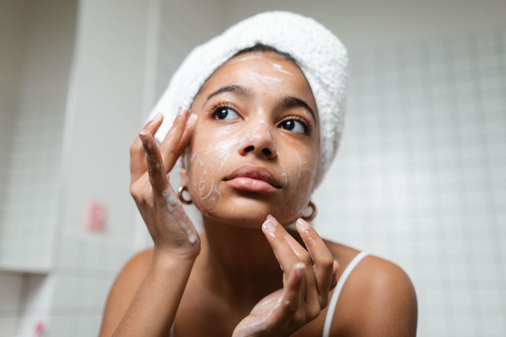 A woman applying skincare at a bathroom mirror