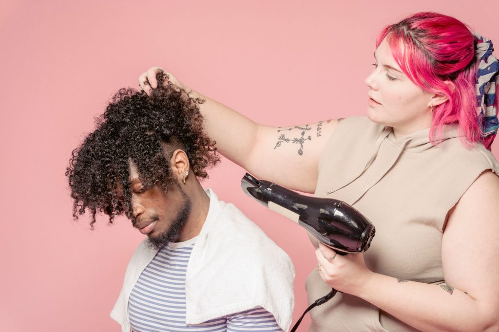 A hairdresser drying a client’s hair with a handheld dryer in a salon