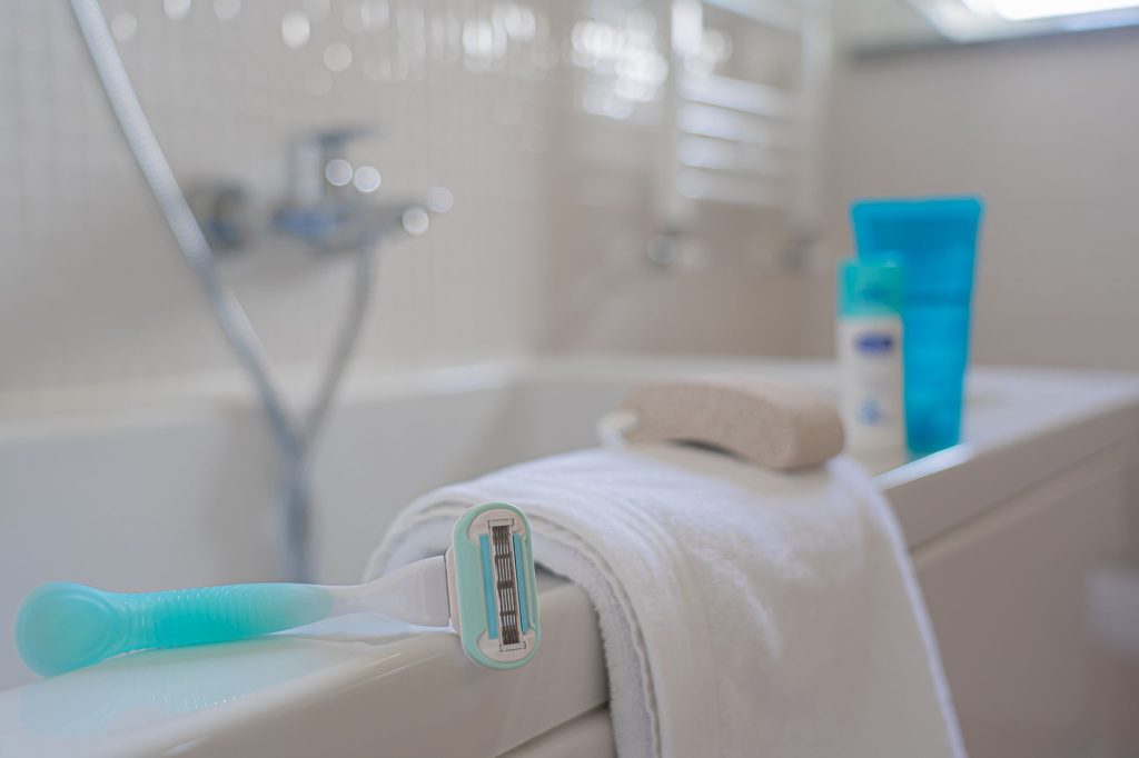 A razor resting on a folded towel beside a bath
