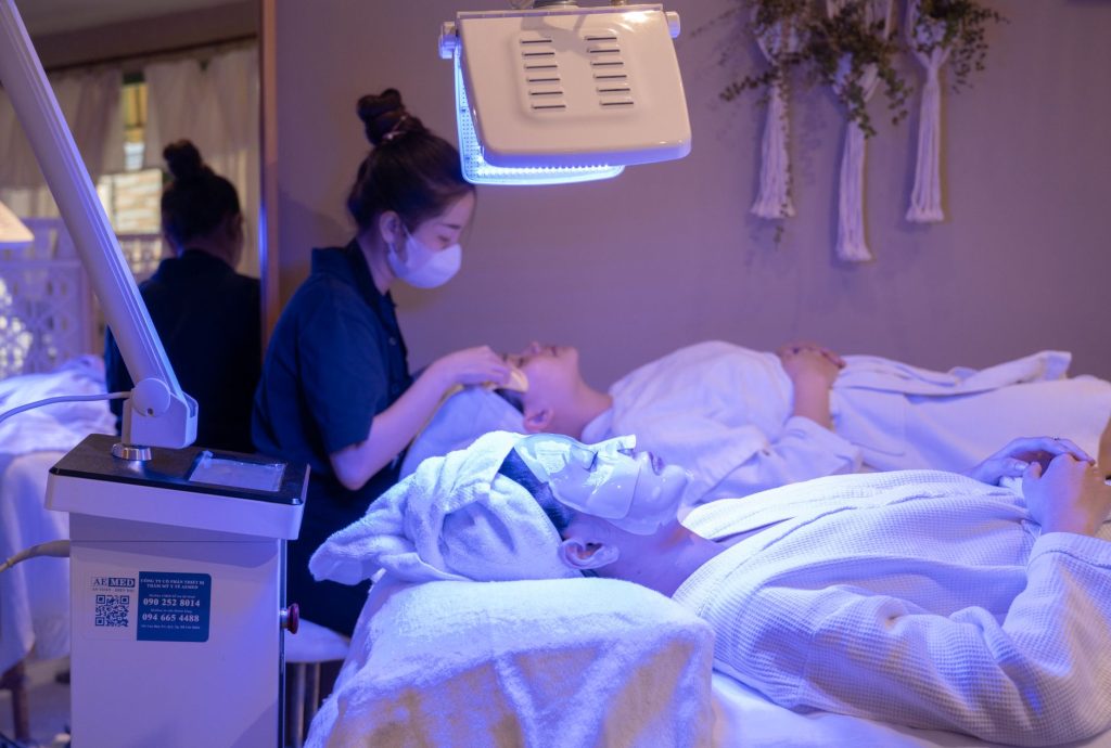A client lying under a blue LED light therapy panel during a facial treatment