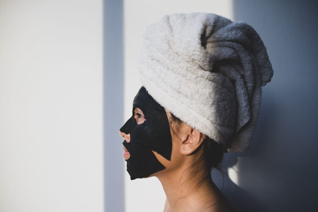 A woman in a towel turban wearing a facial mask, seen in profile