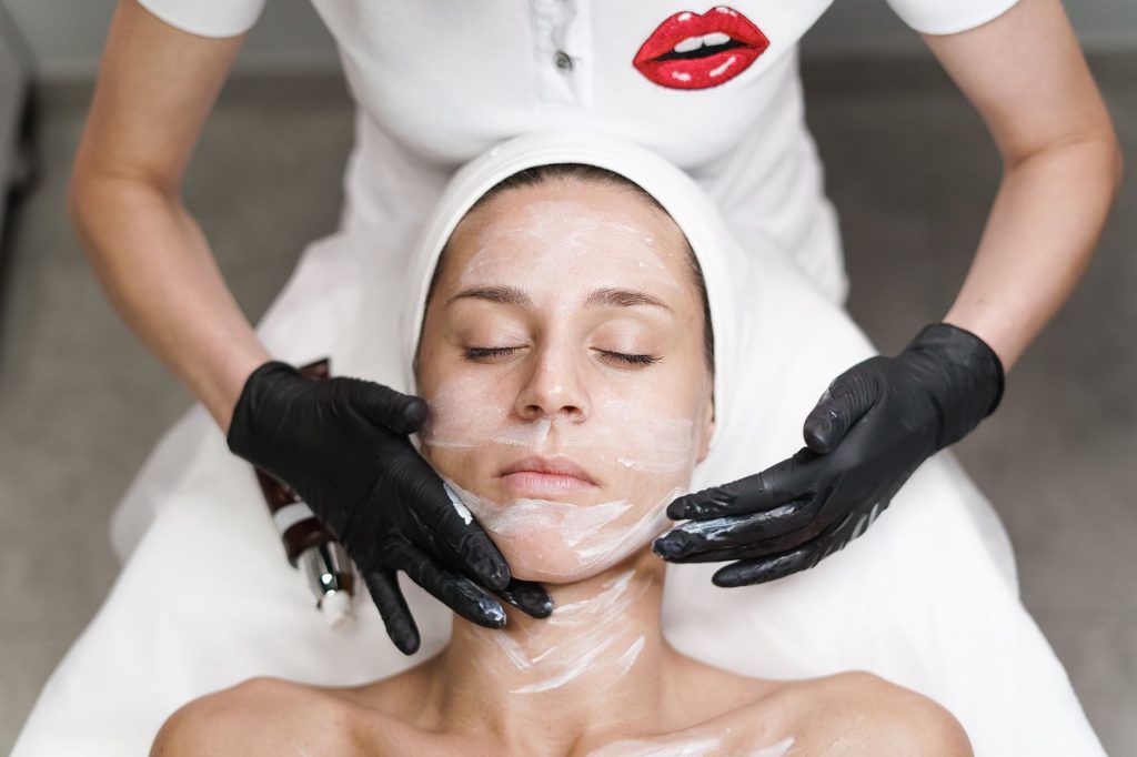 A client receiving a facial treatment under a light panel in a salon