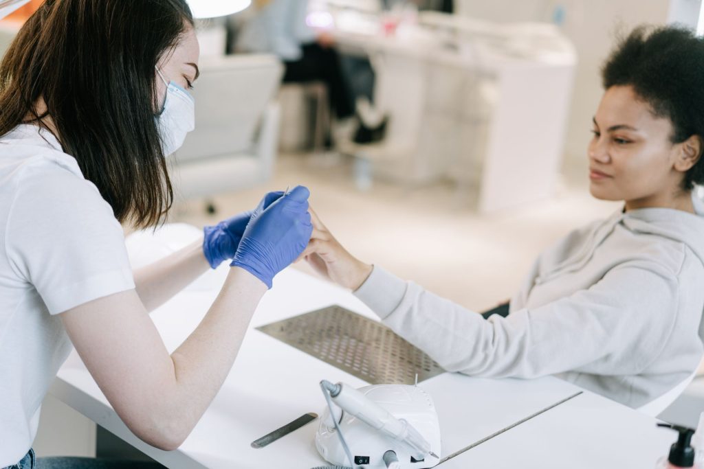 A client having her nails filed at a salon station